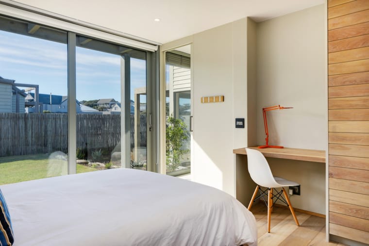 A downstairs bedroom with a desk and doors to the courtyard