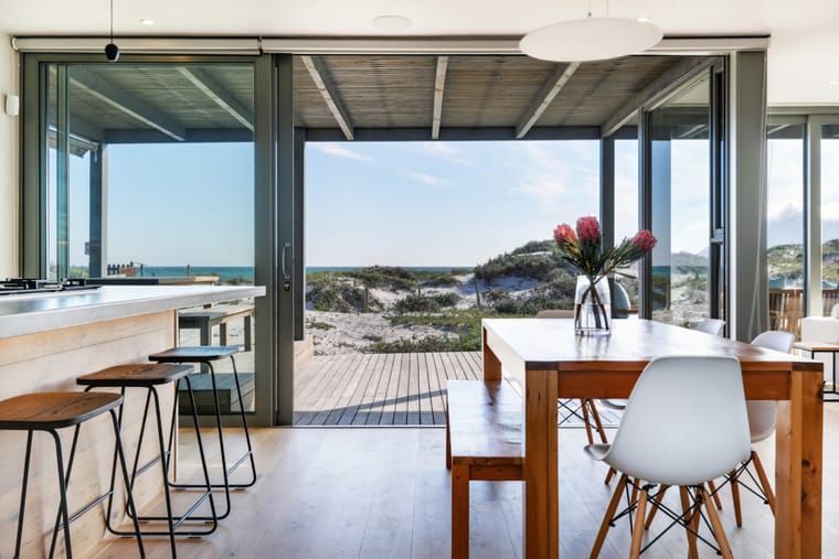 The kitchen island and dining table with the sliding doors open to the deck