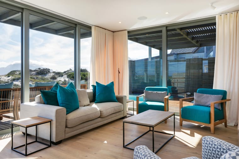 The living room with sofas and armchairs facing the windows and the deck