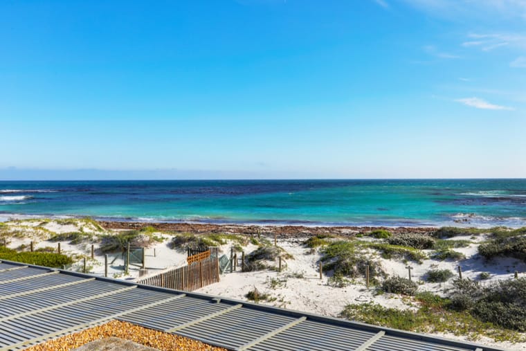 Turquoise water and white sand seen from the deck above the dune
