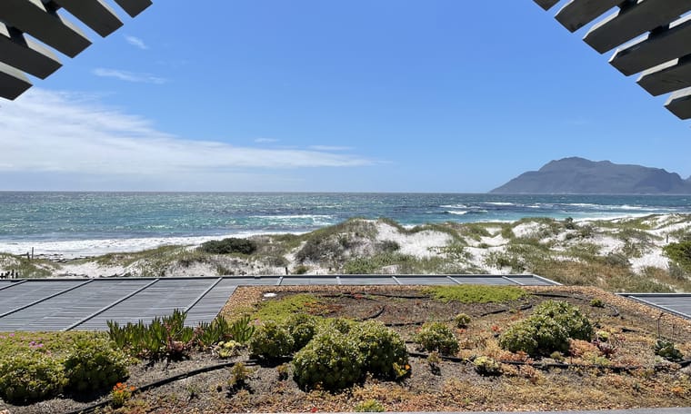 The Atlantic and the mountains of Hout Bay seen from the upper deck, over the green roof and the dune