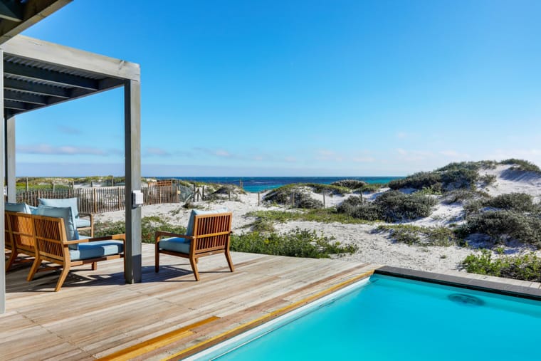 Loungers on the deck beside the pool, looking over the dune to the sea